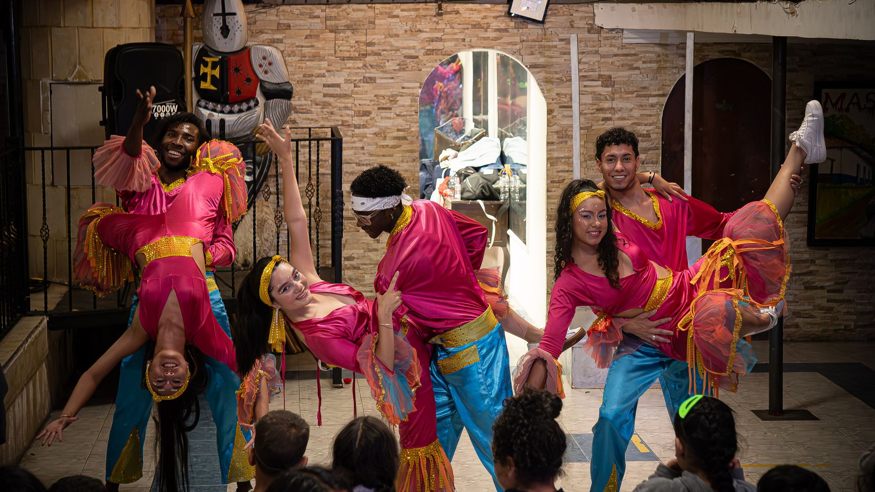 Bailarines de la fundación hacen una figura acrobática frente a niñas y niños