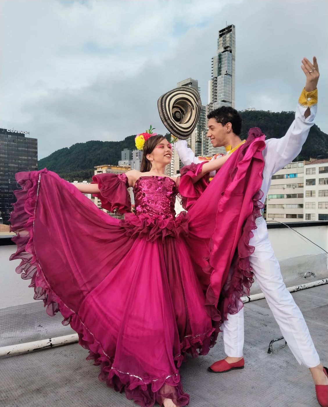 Bailarina con vestido fucsia y sombrero vueltiao en una terraza de Bogotá