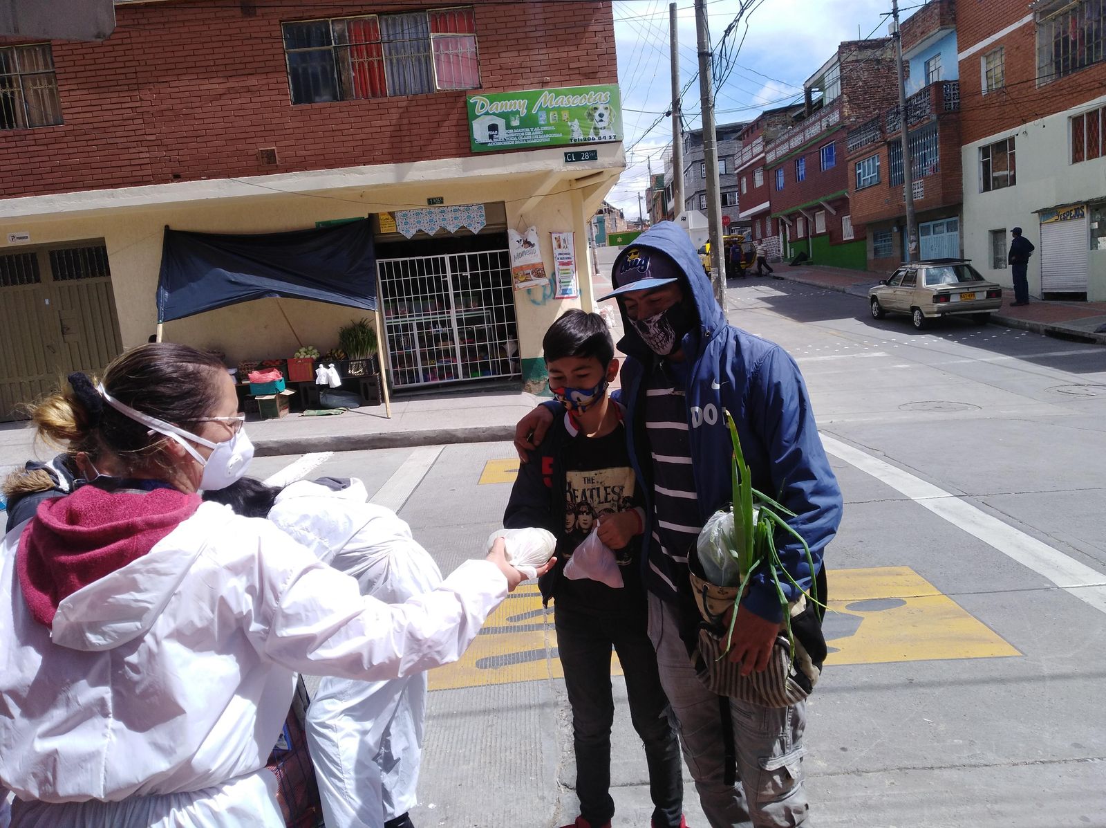 Voluntarias con traje de bioseguridad entregan ayudas en una calle de Bogotá