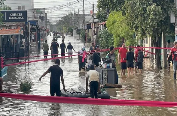 Calle inundada en un pueblo de Colombia, con personas caminando entre el agua