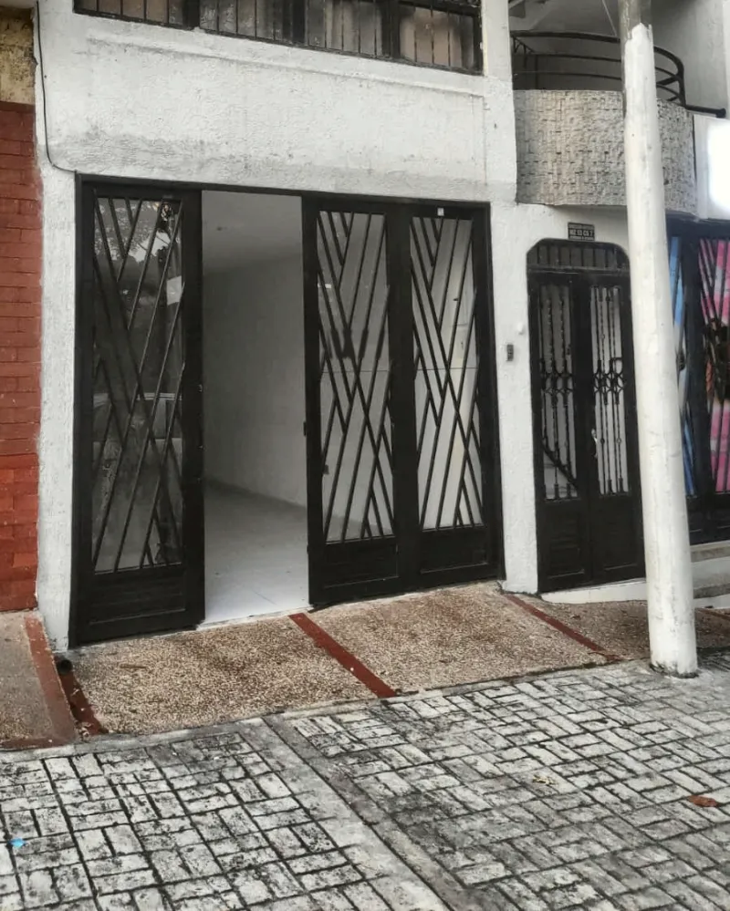 Fachada blanca de la sede en Ibagué, con puertas de reja negra en diagonales
